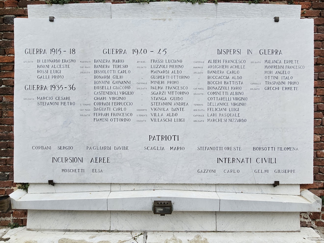 Lapide commemorativa dedicata ai caduti delle guerre, con nomi incisi e dettagli sui dispersi.
