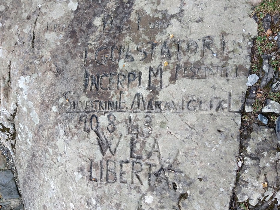 Scritta partigiana incisa su una roccia al Lago Santo, simbolo di lotta per la libertà e la resistenza.