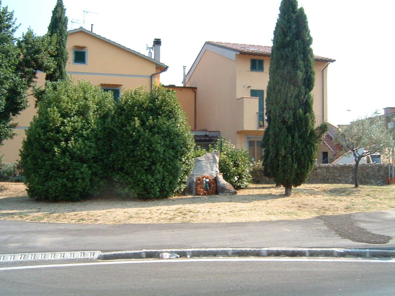 Monumento del quarantennale, commemorazione situata in un'area verde con alberi e case sullo sfondo.