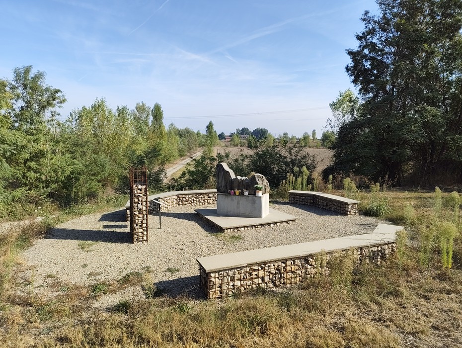 Il Monumento ai Martiri del Panaro si erge in un'area verde circondata da alberi e sentieri.