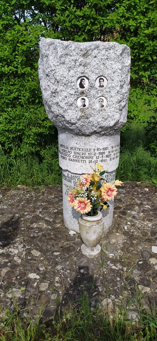 Cippo commemorativo con foto e fiori, circondato da vegetazione. Un tributo a Rusticelli, Simoni, Cremonini e Nannetti.