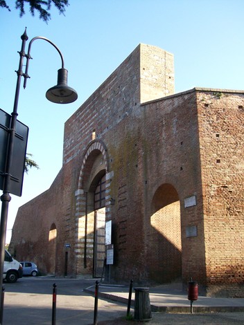 Lapide commemorativa a De Monsabert, affiancata da un imponente muro di mattoni storici.