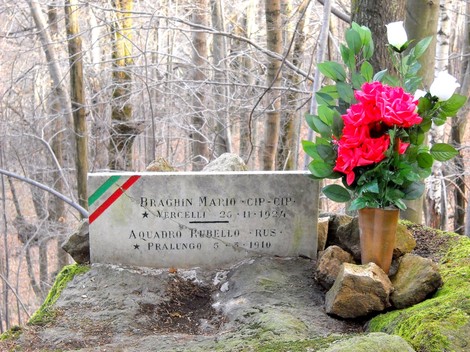 Lapide commemorativa con fiori dedicata a Braghin e Acquadro in un contesto naturale.