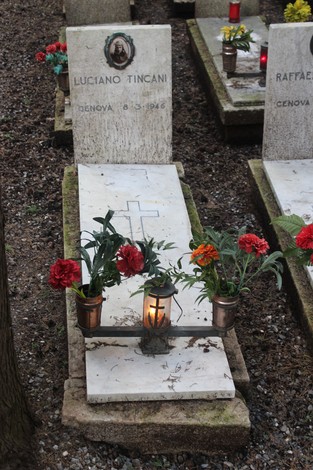 Tombe adornate con fiori e candele, dedicate ai caduti per la Libertà. Atmosfera di rispetto e commemorazione.