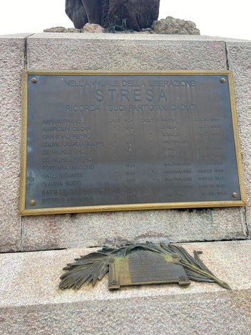 Monumento ai caduti con incisi nomi di partigiani, simbolo di commemorazione e rispetto per la libertà.