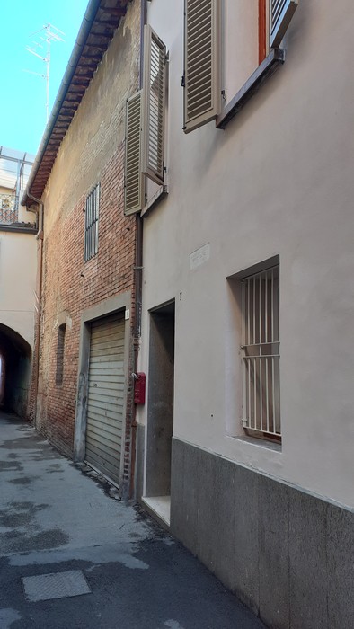 Lapide commemorativa a Noferini, visibile su un muro in un vicolo. Dettagli architettonici circostanti.
