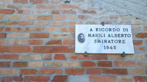 Lapide commemorativa dedicata a Maioli Alberto, smanitatore, del 1945 su un muro di mattoni.