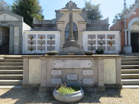 Monumento dedicato ai partigiani, con decorazioni floreali e croce centrale, in un contesto di memoria storica.