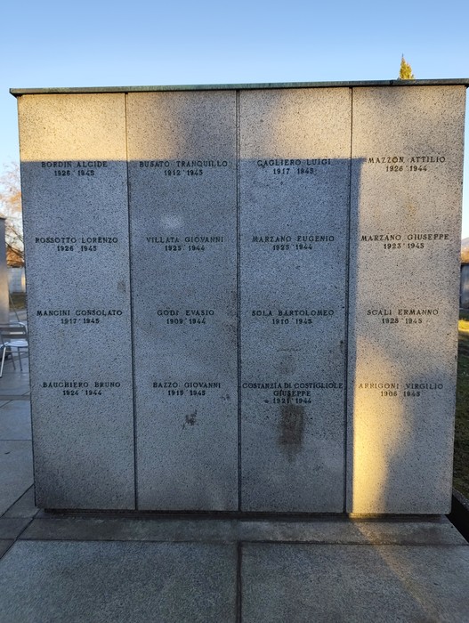 Monumento commemorativo di Campo della Gloria, con nomi e date di caduti in guerra. Atmosfera di rispetto e memoria.