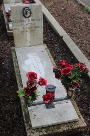 Tomba di Fermino Manfredi Tigrotto con fiori rossi e candele, commemorazione dei caduti per la Libertà.