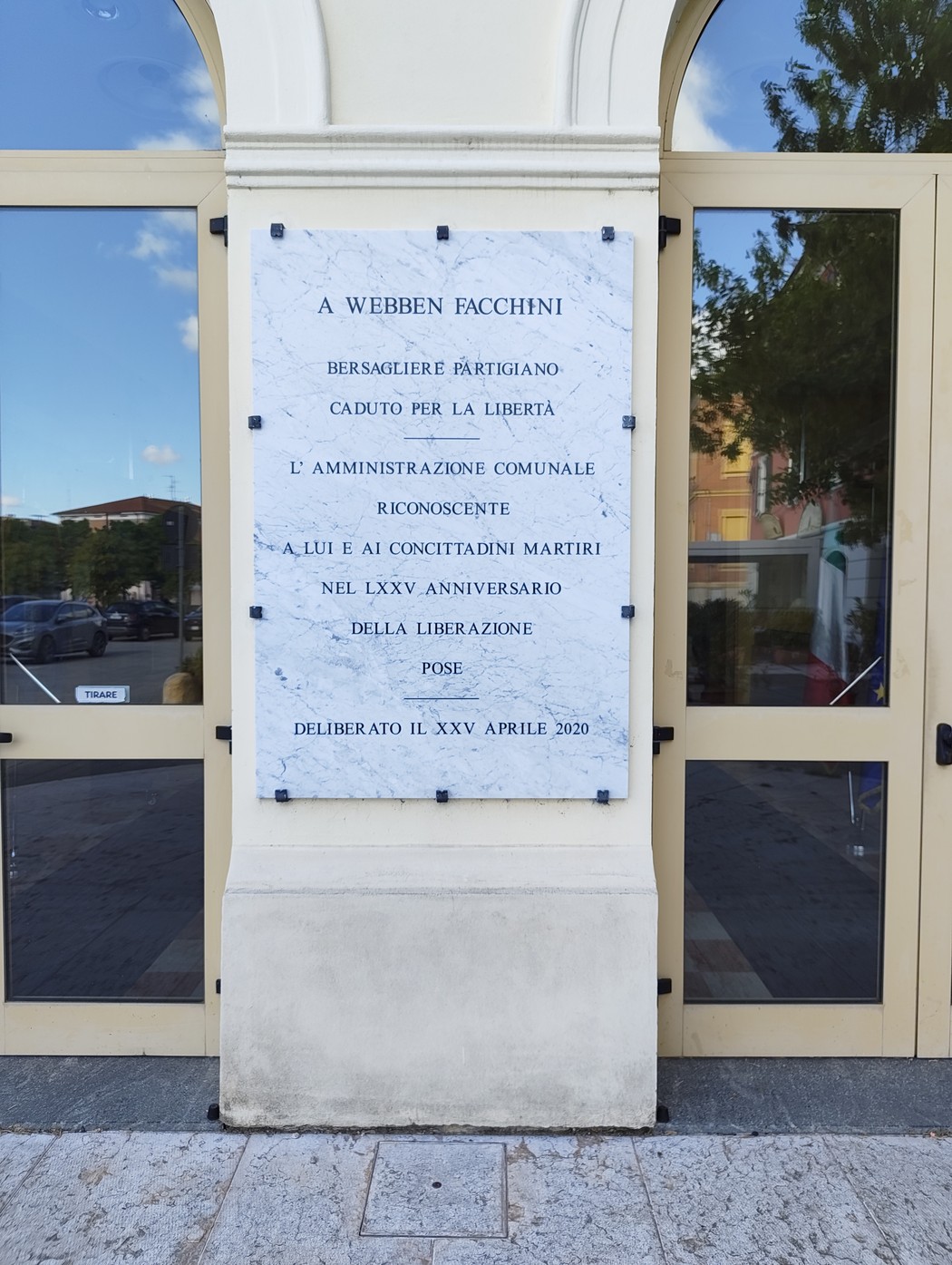 Lapide in marmo dedicata a Webben Facchini, partigiano caduto per la libertà, presso un edificio pubblico.