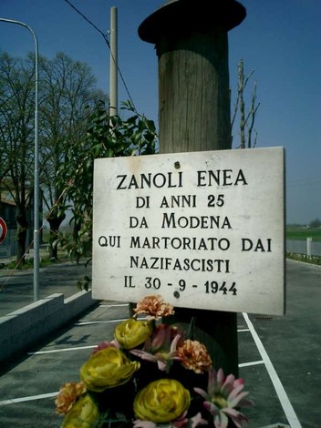 Targa commemorativa dedicata a Enea Zanoli, vittima del nazifascismo a Modena nel 1944, con fiori.
