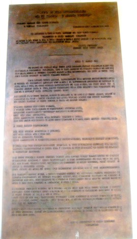 Targa commemorativa che ricorda un importante evento storico, scritta su una superficie metallica.