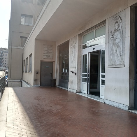 Lapide commemorativa posizionata all'ingresso della Casa dello Studente, con dettagli architettonici.