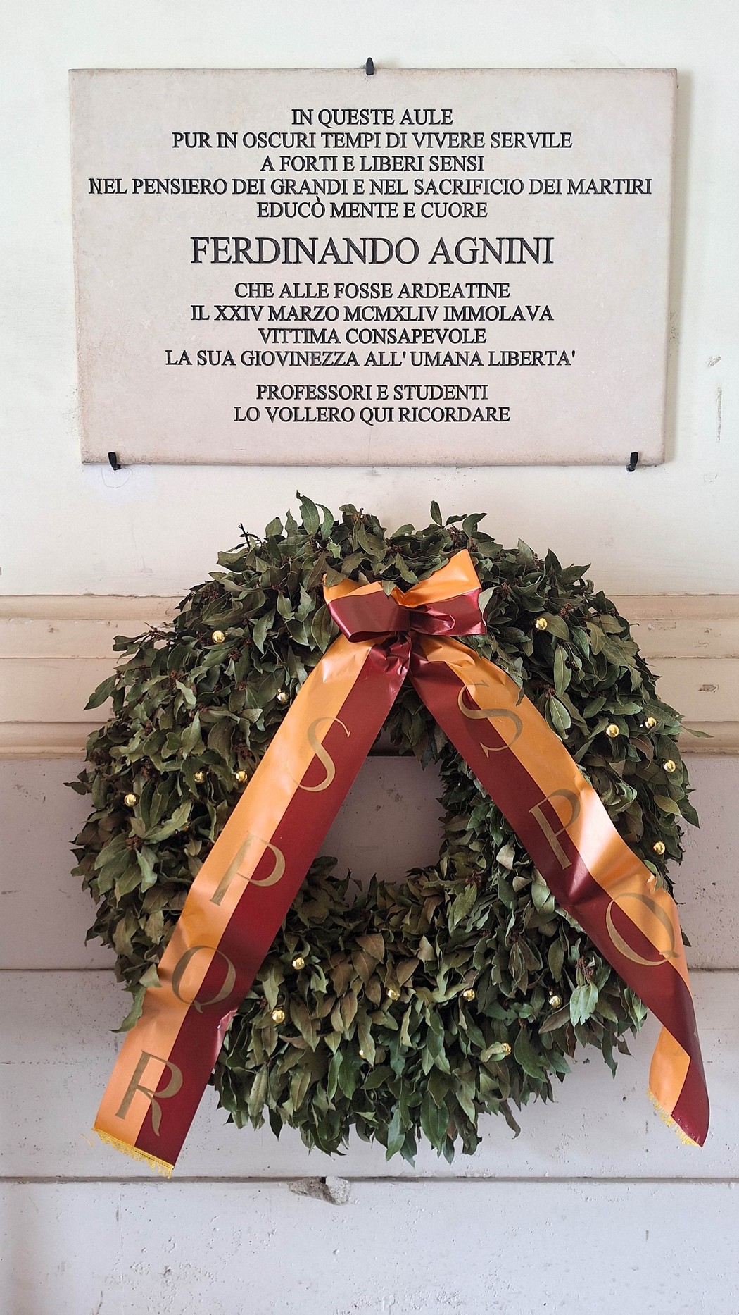 Lapide commemorativa di Ferdinando Agnini, con corona di alloro e nastro, in onore dei sacrifici per la libertà.