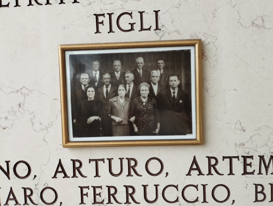 Lapide commemorativa della famiglia Scaltriti con foto di famiglia incorniciata.