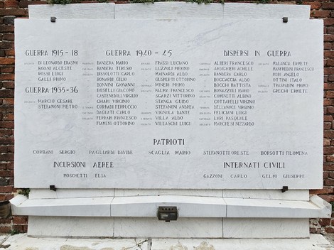 Lapide commemorativa dedicata ai caduti delle guerre, con nomi incisi e dettagli sui dispersi.