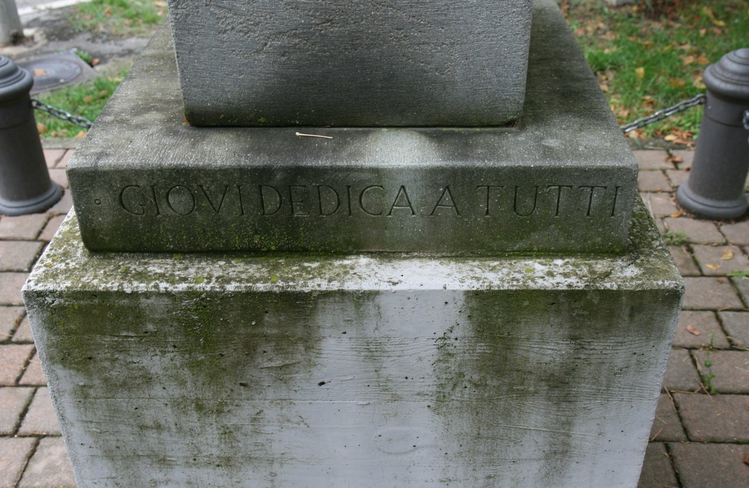Monumento di Giovi, dedicato a tutti, con base in pietra fungerale e contesto verde circostante.
