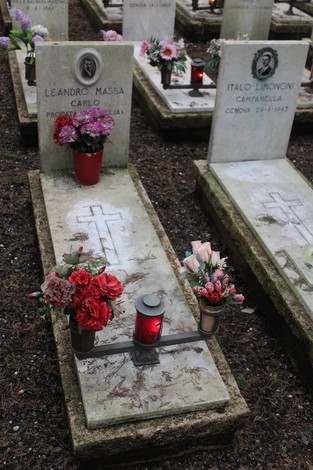 Tombe decorate con fiori e candele, dedicate ai caduti per la Libertà, in un cimitero.