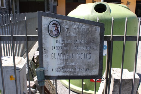 Lapide commemorativa dedicata a Guadagni Phetro, situata in un'area urbana con recinzione.