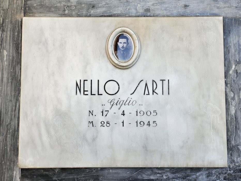 Lapide in marmo con ritratto ovale fotografico e iscrizione dedicata a un caduto.