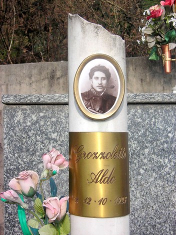 Monumento commemorativo dedicato ai martiri della Garella, con fiori e una foto su una stele.