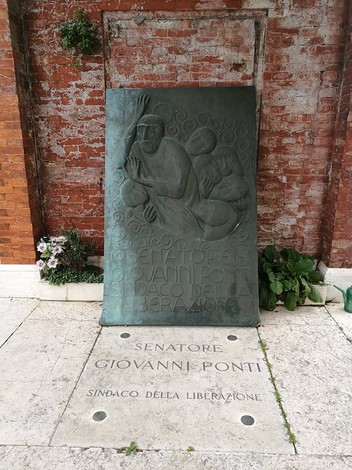 Rappresentazione bronzea dedicata a Giovanni Ponti, con iscrizioni su un basamento in pietra.
