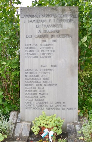 Monumento commemorativo ai caduti di Frassineti, circondato da vegetazione, con nomi di soldati incisi.
