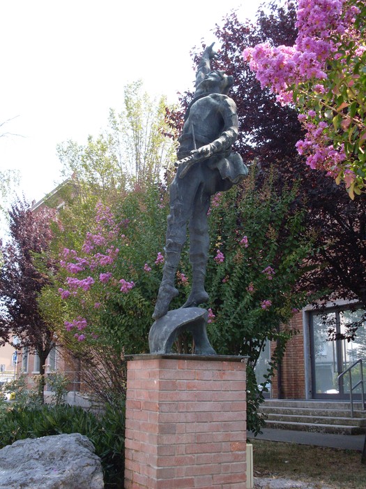 Monumento ai Partigiani, scultura commemorativa circondata da fiori e vegetazione, simbolo di resistenza e libertà.