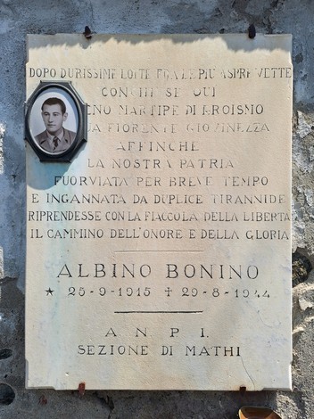 Lapide commemorativa dedicata ad Albino Bonino, martire del eroismo, incastonata in un muro di pietra.