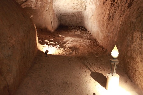 Interno delle Fosse Ardeatine, con pareti rocciose e un'illuminazione soffusa che mette in evidenza l'ambiente storico.