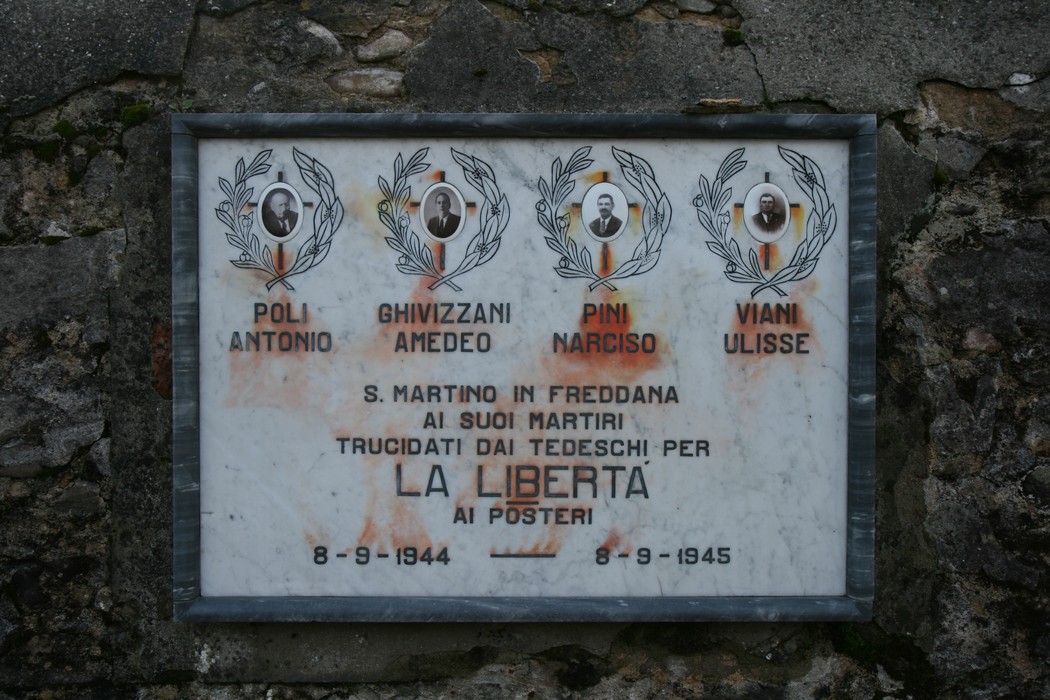 Lapide commemorativa ai martiri di San Martino, vittime della guerra, con i loro nomi e date di commemorazione.