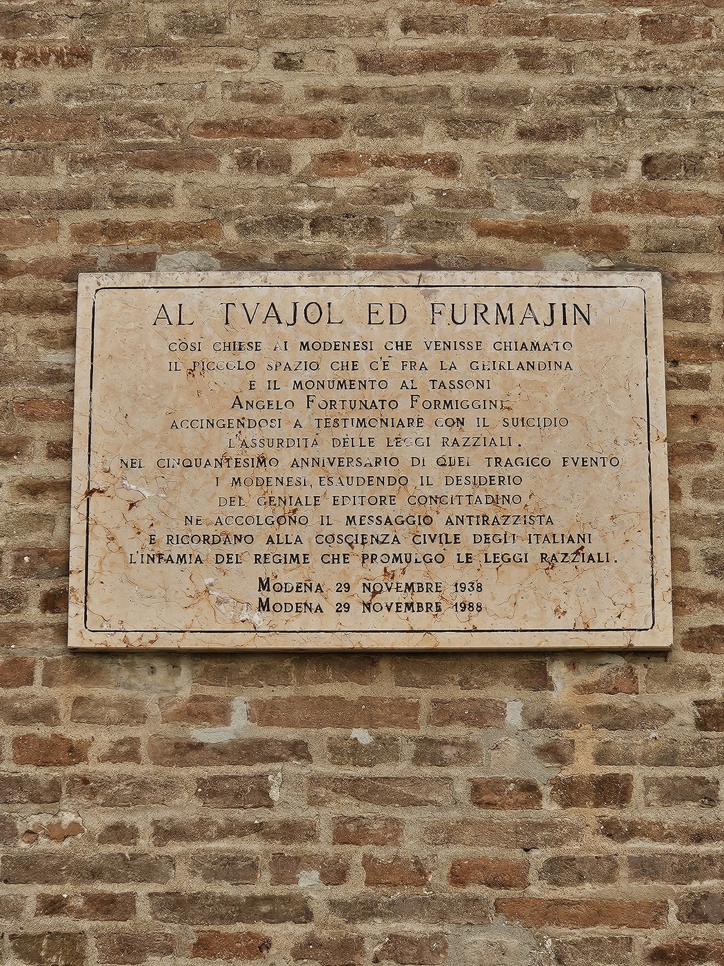Lapide commemorativa dedicata a Angelo Fortunato Formiggini, inserita in un contesto storico e culturale.