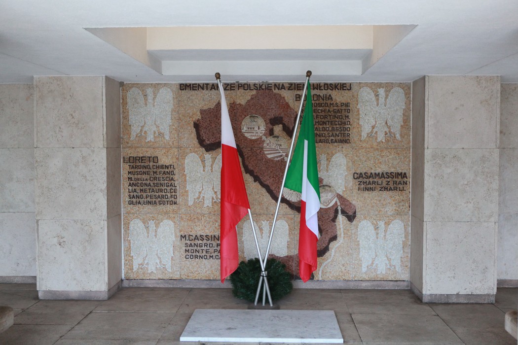 Monumento commemorativo con bandiere polacche e italiane, dedicato ai soldati polacchi. Ambiente sobrio e rispettoso.