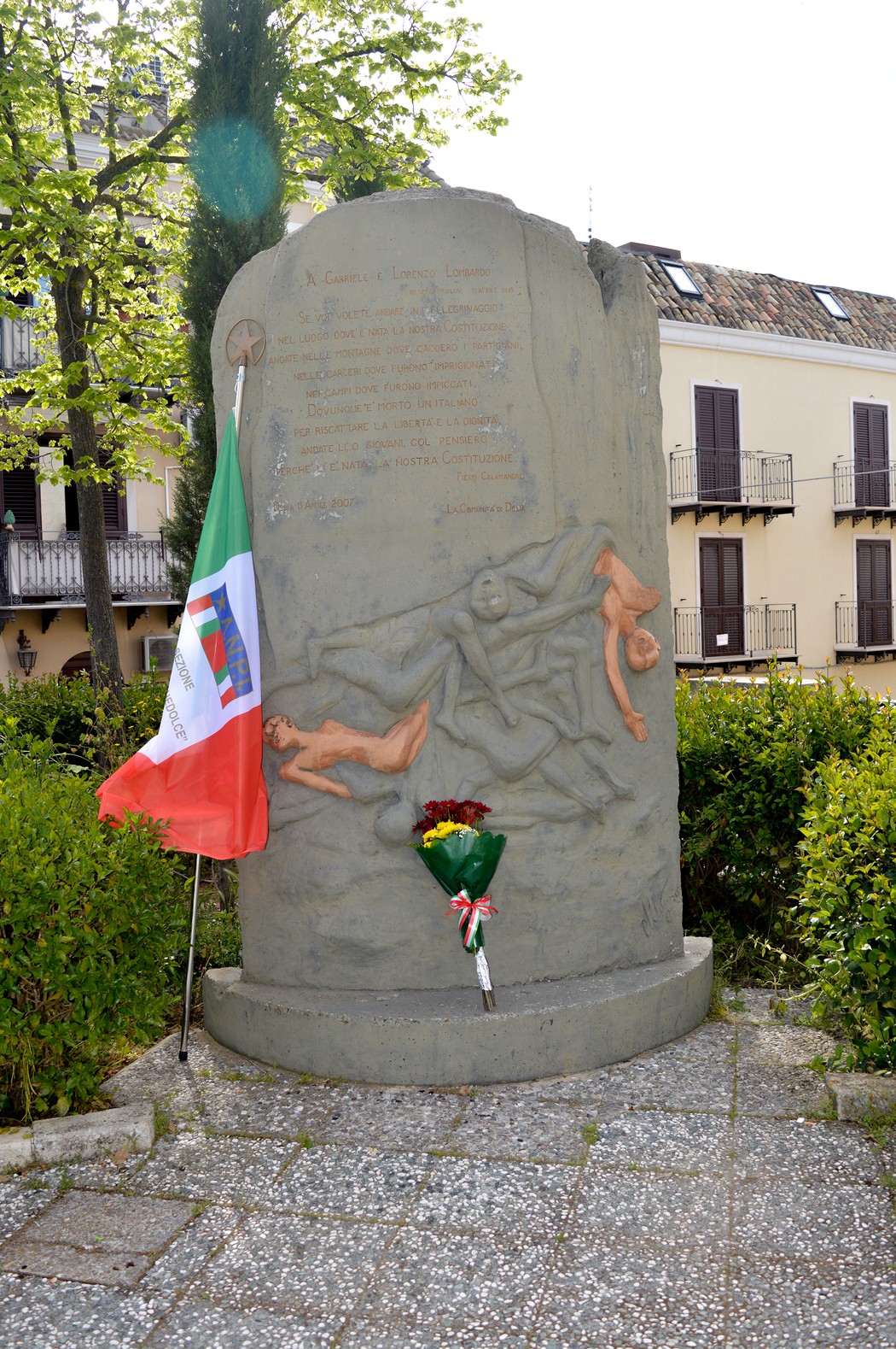 Monumento ai Lombardo, dedicato alla memoria e al sacrificio, con scultura e omaggio floreale.