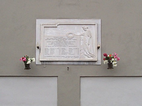 Lapide commemorativa dell'Istituto Farmaceutico Militare, decorata con fiori.