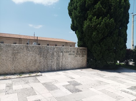 Monumento ai caduti della Resistenza, circondato da un giardino e una vegetazione curata.