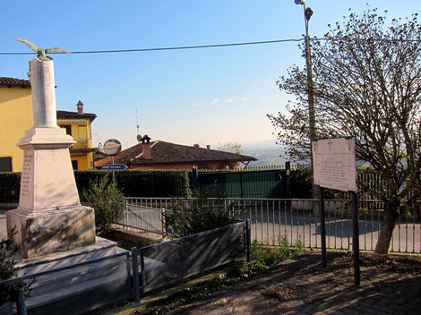 Monumento a Vercesi con vista panoramica, circondato da alberi e abitazioni in un contesto tranquillo.