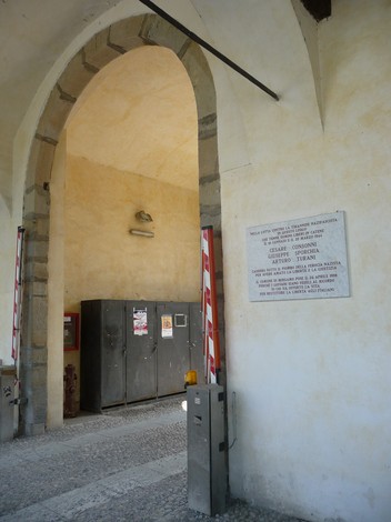 Lapide commemorativa dedicata a Turani, Sporchia e Consonni, situata in un'area di passaggio architettonica.