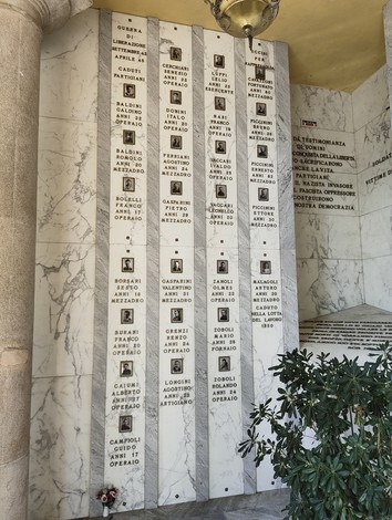 Sacrario dei caduti, monumento commemorativo con nomi incisi su lastre di marmo, ambiente sobrio e solenne.