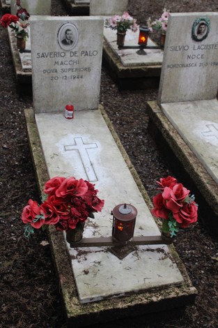 Tombe con fiori e candele in onore dei caduti per la Libertà, simbolo di memoria e rispetto.