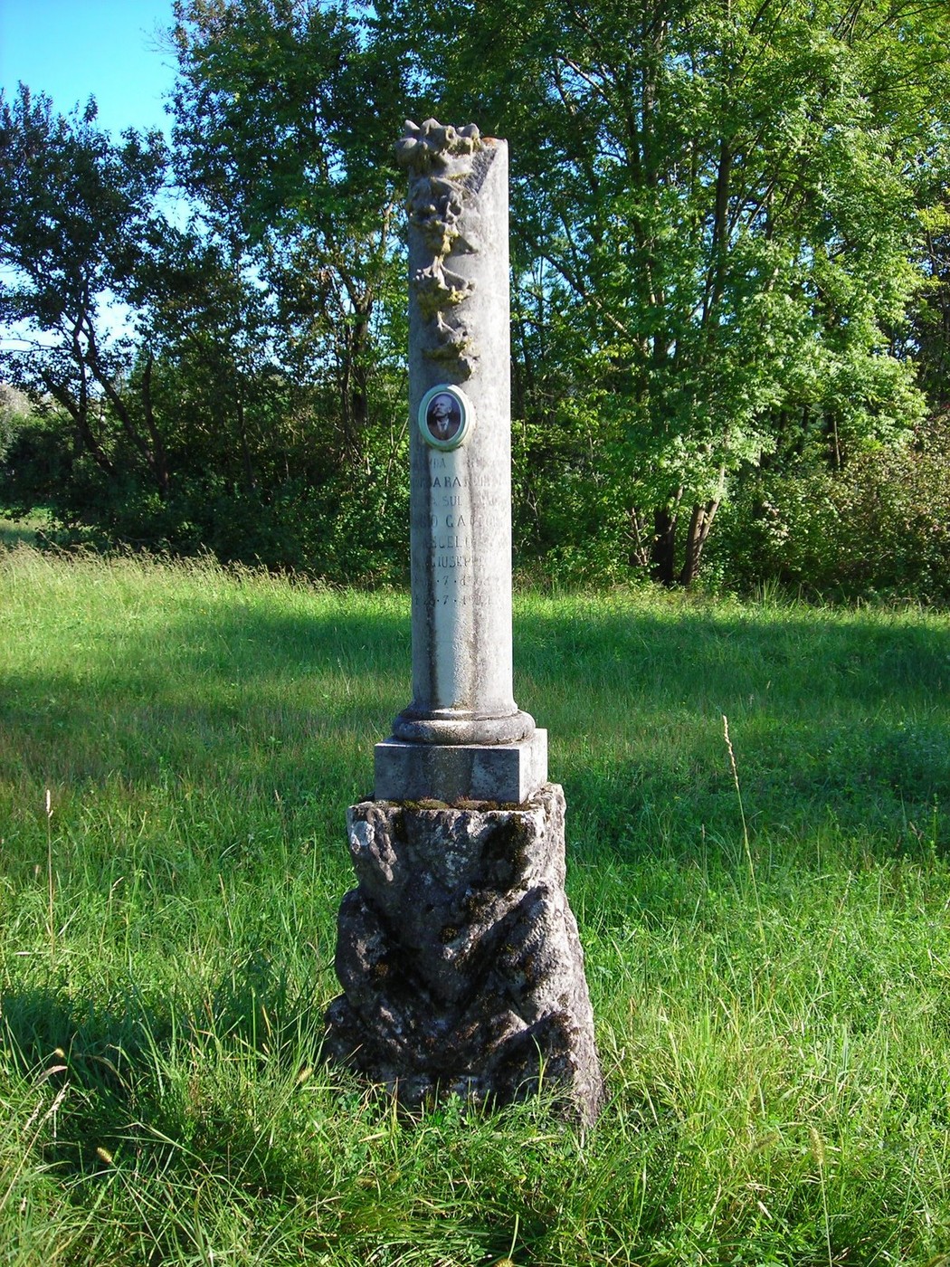 Cippo commemorativo immerso nel verde, simbolo di memoria e storia locale.