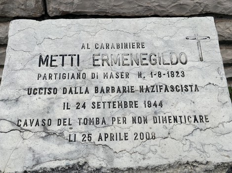 Cippo commemorativo dedicato a Metti Ermenegildo, partigiano ucciso nel 1944, con data e messaggi di ricordo.