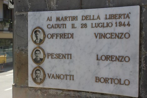 Cippo commemorativo in marmo dedicato ai martiri della libertà a Offredi, Pesenti e Vanotti, con ritratti.