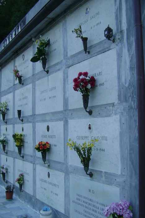 Sepolcri dedicati ai caduti per la libertà, con fiori e nomi incisi in memoria dei soldati.