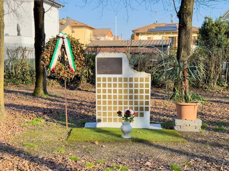Il Giardino della Memoria con un monumento commemorativo e decorazioni floreali in un ambiente sereno.