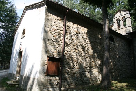 Oratorio di Vallucciole, edificio in pietra immerso nella natura, con campanile e silenziosa atmosfera spirituale.