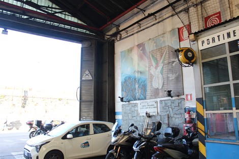 Murale commemorativo alla Resistenza, visibile all'interno di un garage con moto e auto parcheggiate.