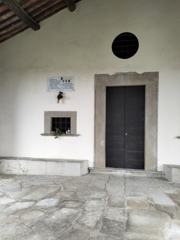 Lapide commemorativa dedicata ai caduti di Valloni, situata in un edificio con porta e finestre.
