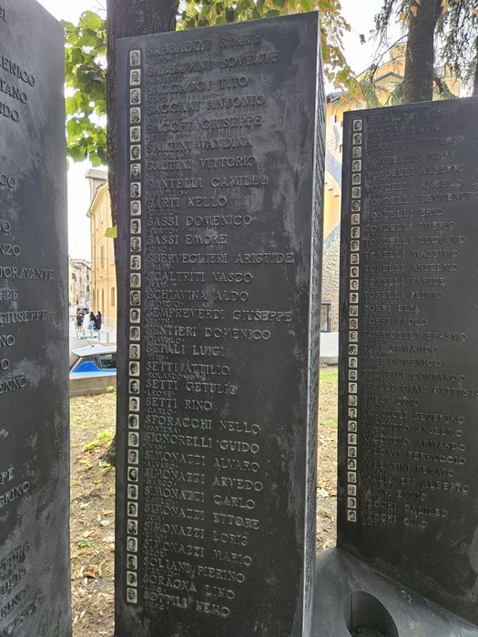 Monumento formato da lastre scure incise con iscrizioni e nomi, in uno spazio alberato.